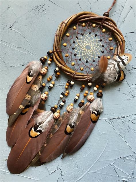A Dream Catcher With Feathers And Beads Hanging From Its Side On A Wall