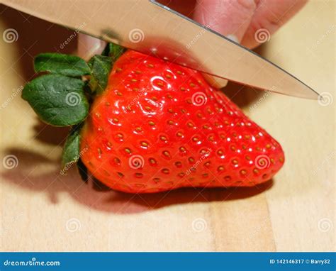 Strawberry Being Cut In Half On Wooden Chopping Board Stock Image