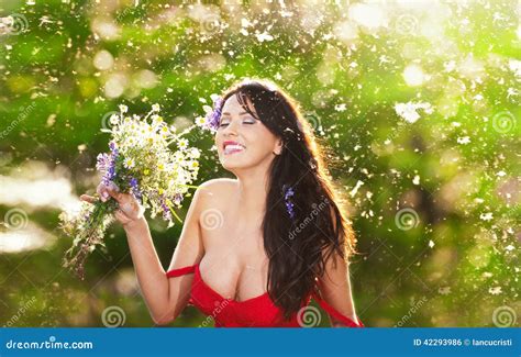 Young Voluptuous Brunette Holding A Wild Flowers Bouquet In A Sunny Day Portrait Of Beautiful