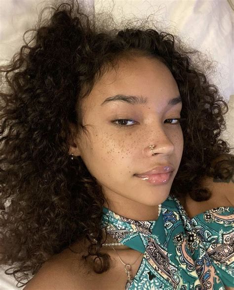 a woman laying in bed with freckles on her head and wearing a green shirt