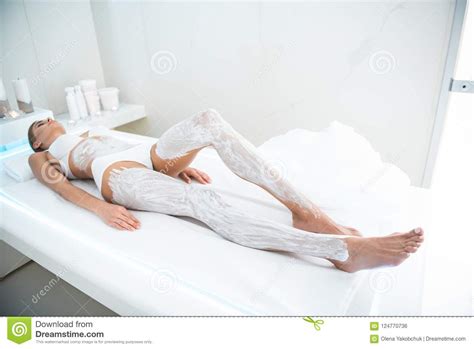 Young Lady Lying On Massage Table With Cosmetic Mask On Legs And Belly