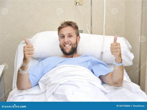 Young American Man Lying In Bed At Hospital Room Sick Or Ill But Giving