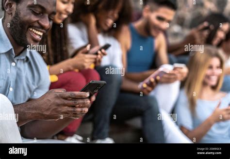 Young Multiracial Group Of Friends Using Mobile Smartphone Sitting On