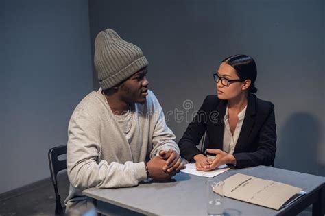 Una Abogada Con Gafas Y Un Joven Negro Se Comunican En La Sala De Interrogatorios Sobre Los