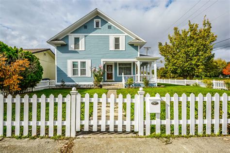 Front View Of A Victorian Style Home With A White Picket Fence The