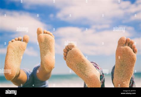 Close Up Of Two Pairs Of Feet On Beach Covered In Sand Stock Photo Alamy