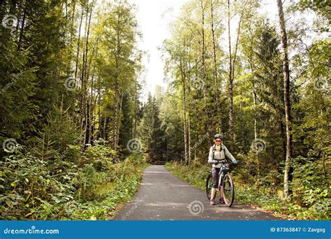 Female Tourist Cyclist Standing On Road In Forest Looking To C Stock