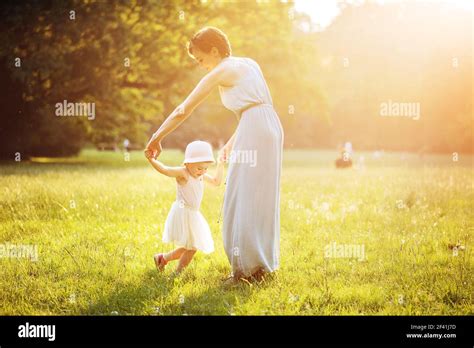 Attractive Mother Dancing With Her Daughter On The Meadow Stock Photo
