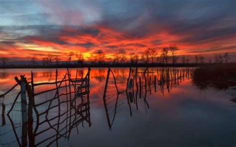 Wooden Fence On Water Under Red Black Clouds Sky Reflection On River Hd