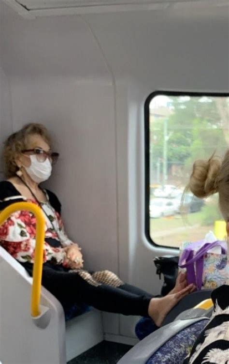 woman wearing a face mask on a packed sydney train is blasted for putting her bare feet on the
