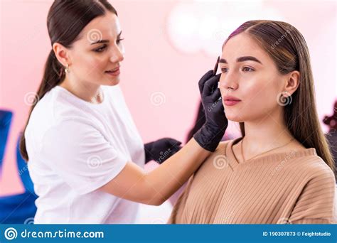 professional visagiste doing makeup contouring brows for woman in beauty salon stock image