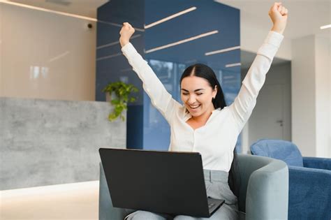 Premium Photo Portrait Of Excited Young Caucasian Woman Celebrating Success While Sitting With