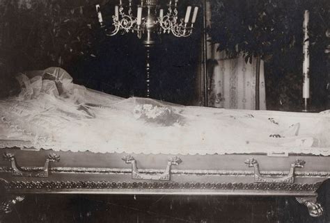 An Old Black And White Photo Of A Woman Laying In A Bed With A Veil On It