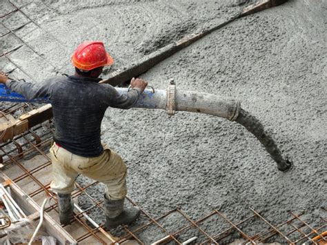 Group Of Construction Workers Pouring Wet Concrete Using Concrete Hose