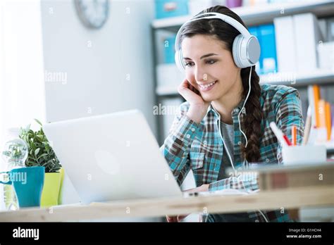 Teenage Smiling Girl Using A Laptop And Wearing Headphones Technology