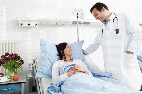 A Doctor Talking To A Smiling Patient Lying In A Hospital Bed Stock