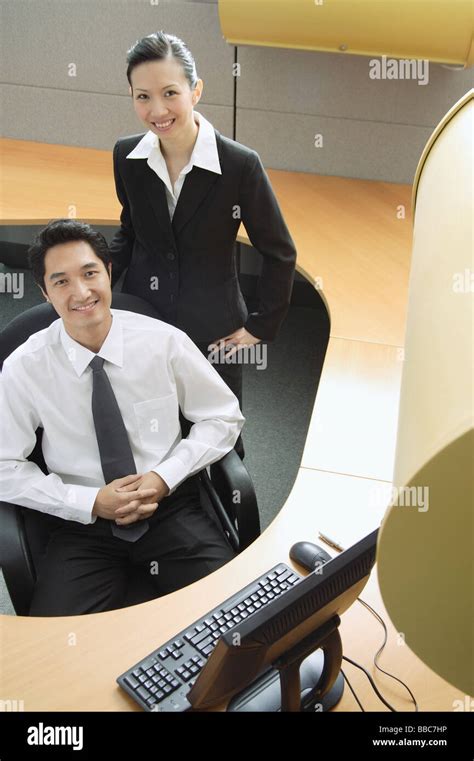 Businessman And Woman In Office Cubicle Smiling At Camera Stock Photo
