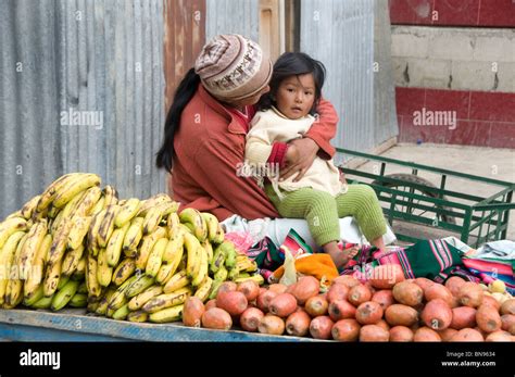 Woman Looking After Her Child While She Works On A Market Stall Selling