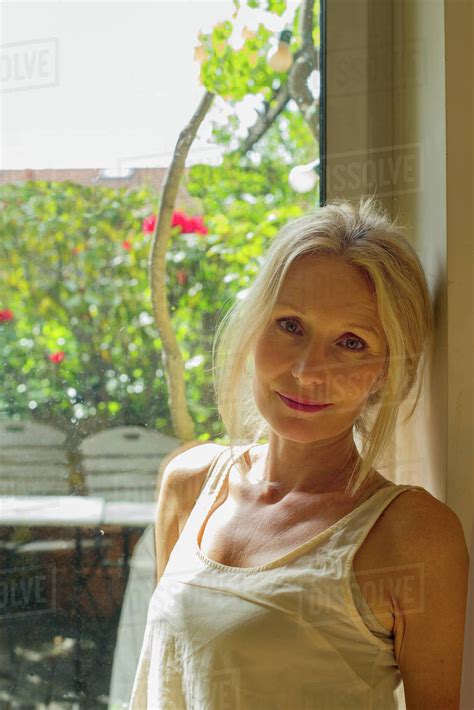 Mature Woman Leaning Against Window Portrait Stock Photo Dissolve