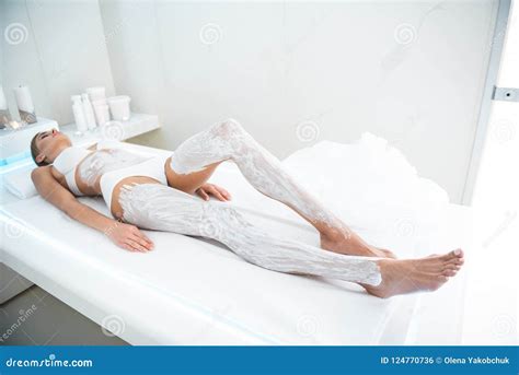 Young Lady Lying On Massage Table With Cosmetic Mask On Legs And Belly