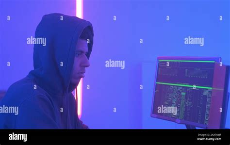 Profile View Of African Hacker In Hoodie Working In Room Filled With