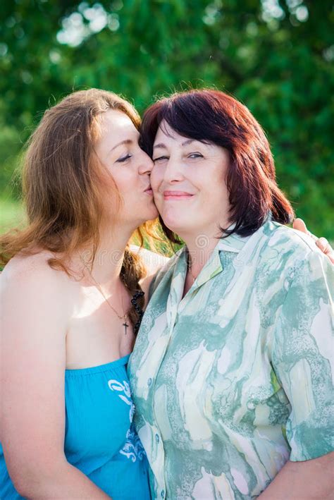 Portrait Daughter Is Kissing Her Mother On The Cheek In The Summer