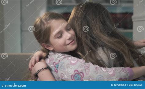 Two Sisters Cuddle Each Other Close Up Smaller And Older Girls Rub Their Noses And Smile