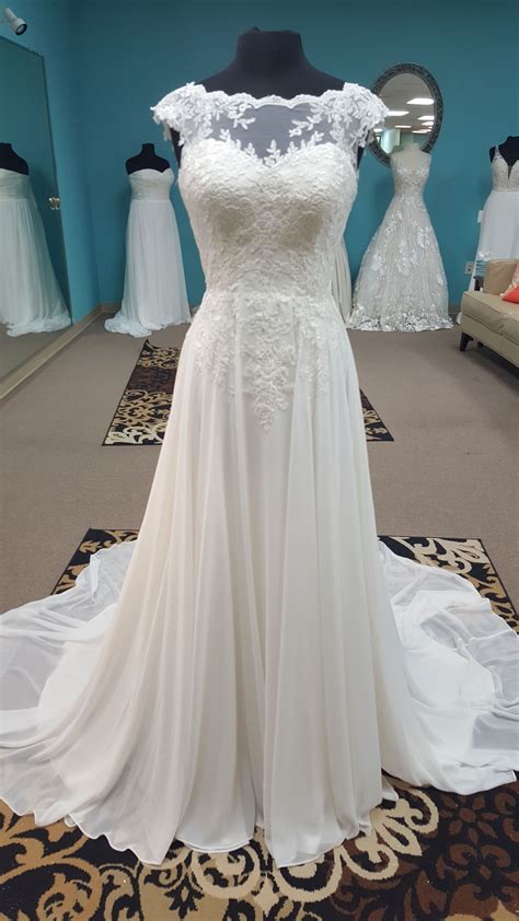 This Elegant Cap Sleeved Wedding Gown Has A Sheer Overlay With Lacy