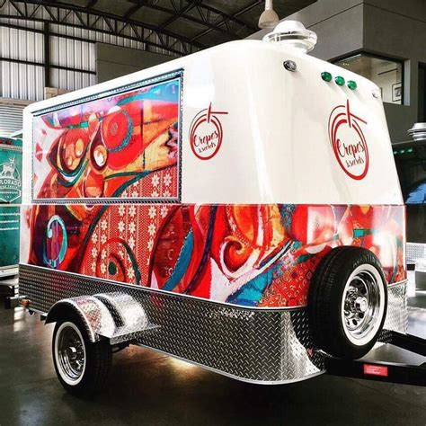 A Food Truck Is Parked In A Building With An Artistic Design On The Side And Sides