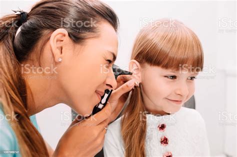 Smiling Doctor Examining Child Ear Using Otoscope Stock Photo