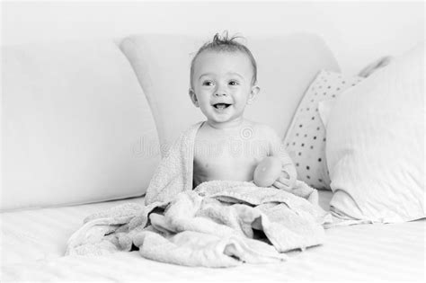 Black And White Portrait Of Laughing Baby Sitting On Bed After H Stock