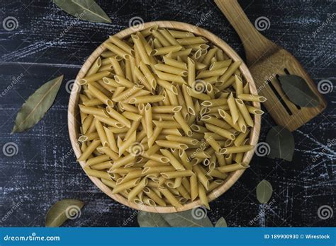 Raw Pasta Penne Rigati Macaroni In A Bowl With Bay Leaves And A Wooden