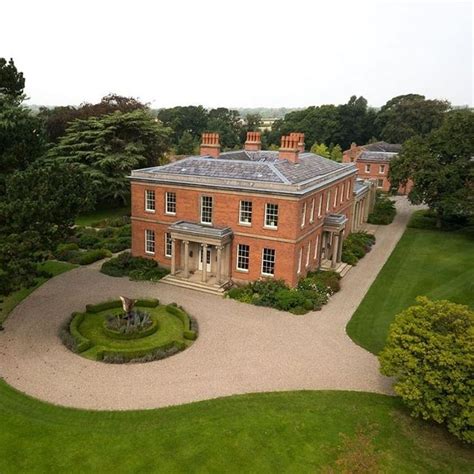 An Aerial View Of A Large Red Brick House In The Middle Of A Lush Green