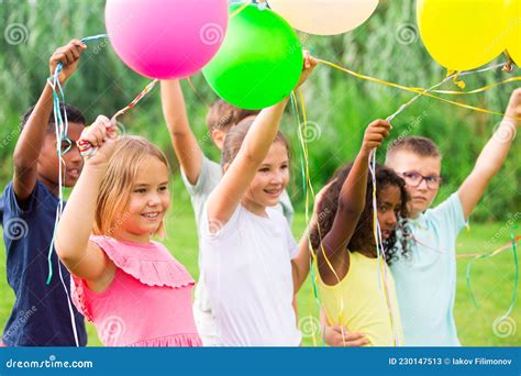 Happy Tweens With Balloons On Green Meadow In Summer Park Stock Image