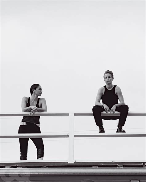 Two People Sitting On Top Of A Metal Rail Next To Each Other In Black