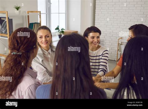 Happy Women Sitting In Circle And Holding Hands In Corporate Meeting Or
