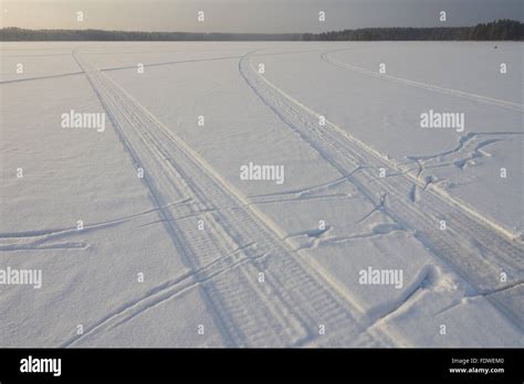 Snowmobile Traces On Snow Of The Frozen Lake In Winter In The