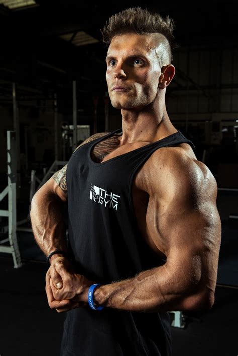 A Man Posing For The Camera In A Gym With His Arms Crossed And Looking