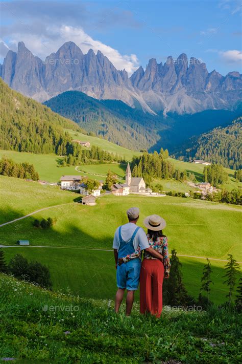 Couple Viewing The Landscape Of Santa Maddalena Village Val Di Funes