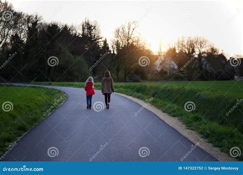 The Sisters Go Along The Empty Road In The Evening Stock Photo Image