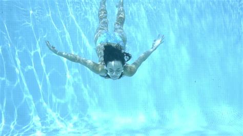 Girl Swimming Underwater In A Swimming Pool Through Sparkling Sunlit