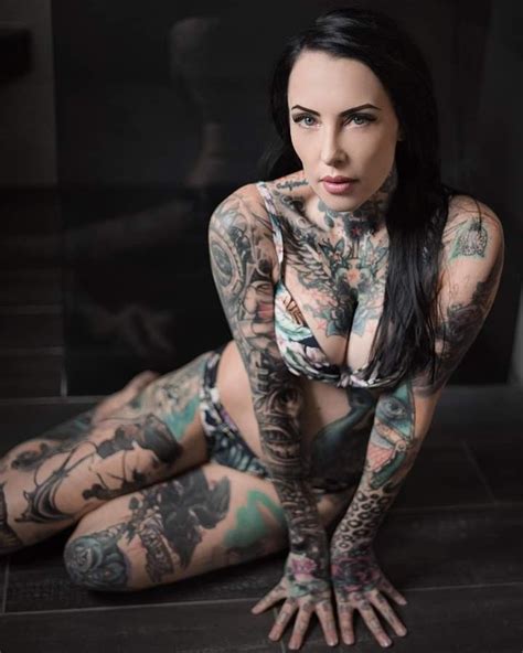 A Woman With Lots Of Tattoos On Her Body Posing For A Photo In Front Of