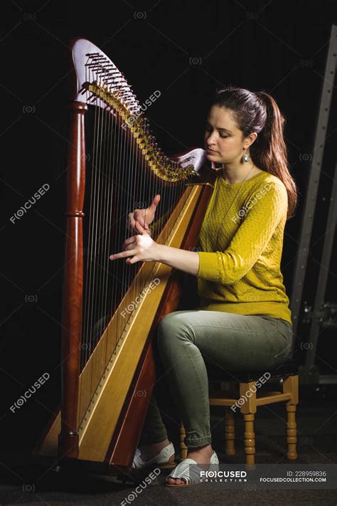 Attentive Woman Playing A Harp In Music School — Tune Soundboard