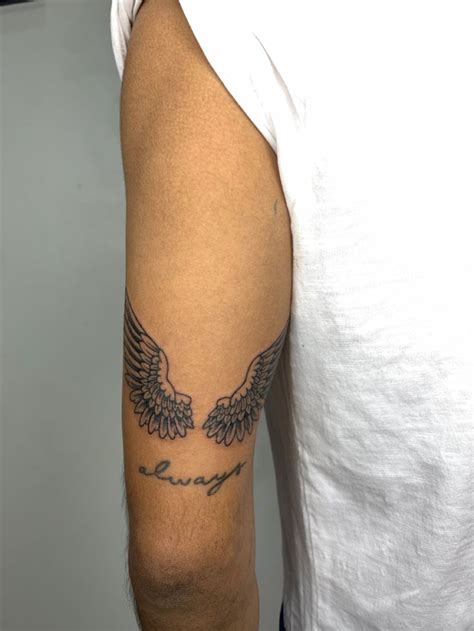 A Man With A Tattoo On His Arm That Has Wings And The Word Love Written