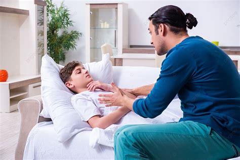 El Joven Padre Cuidando A Su Hijo Enfermo El Joven Padre Cuidando A Su