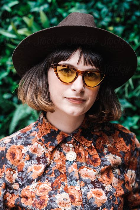 stylish woman wearing floral outfit and sunglasses looking at camera by stocksy contributor