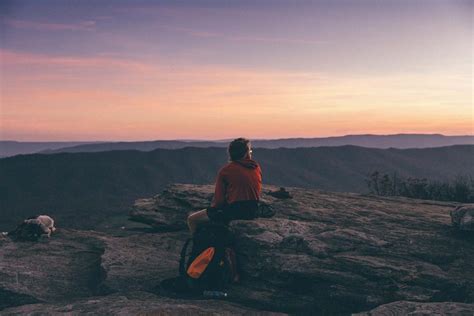 Person Person Sitting On Boulder Overlooking Mountain During Golden