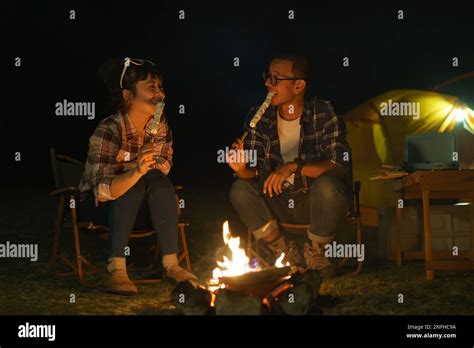 Asian Couple Roasting Marshmallows Together At A Campfire Where They