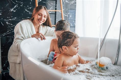 Une Jeune Mère Aide Son Fils Et Sa Fille Deux Enfants à Se Laver Dans Le Bain Photo Premium
