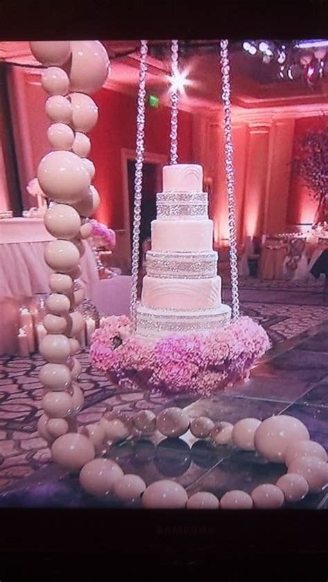 A Wedding Cake Sitting On Top Of A Table In Front Of A Tv Screen With